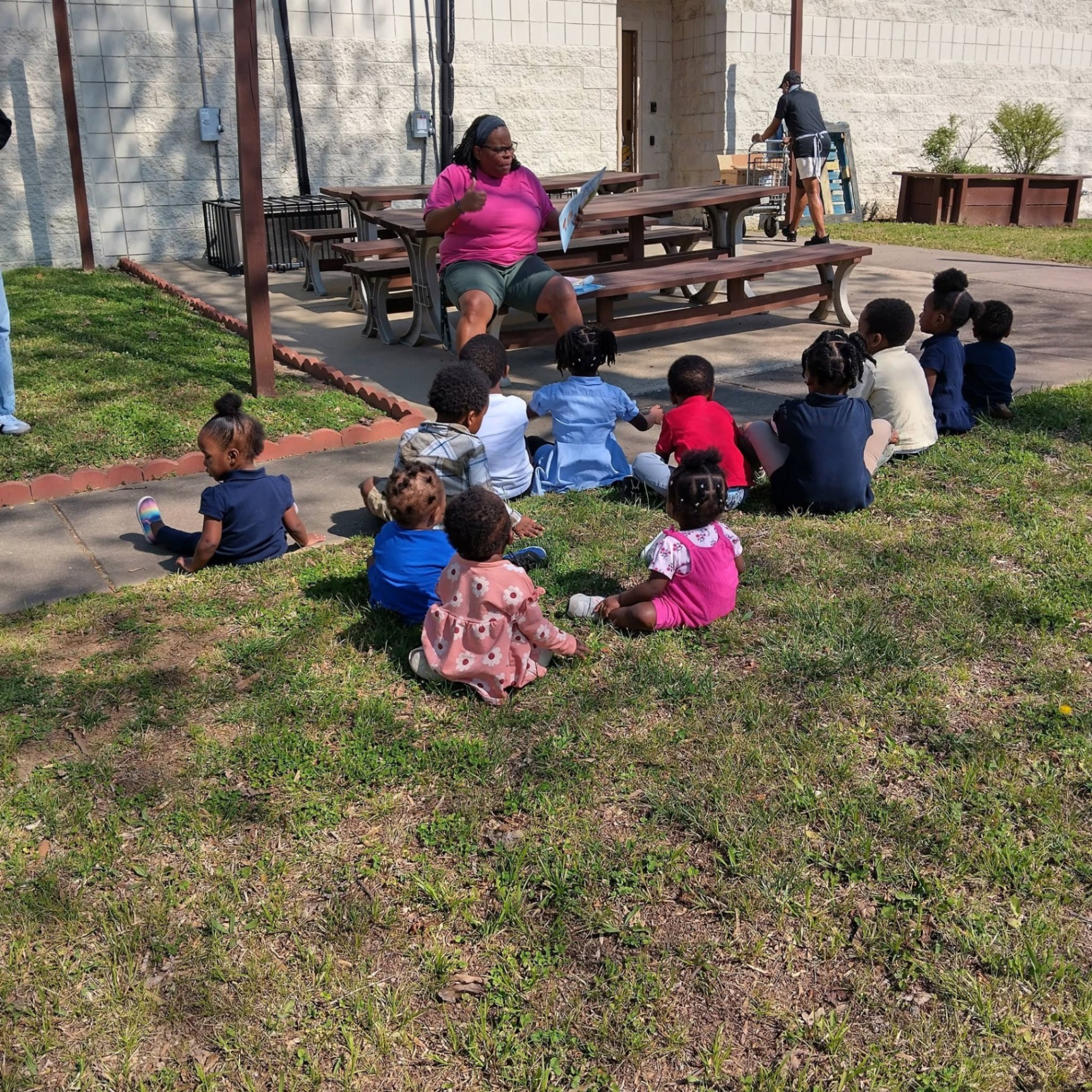 Teacher reading to a circle of children outside