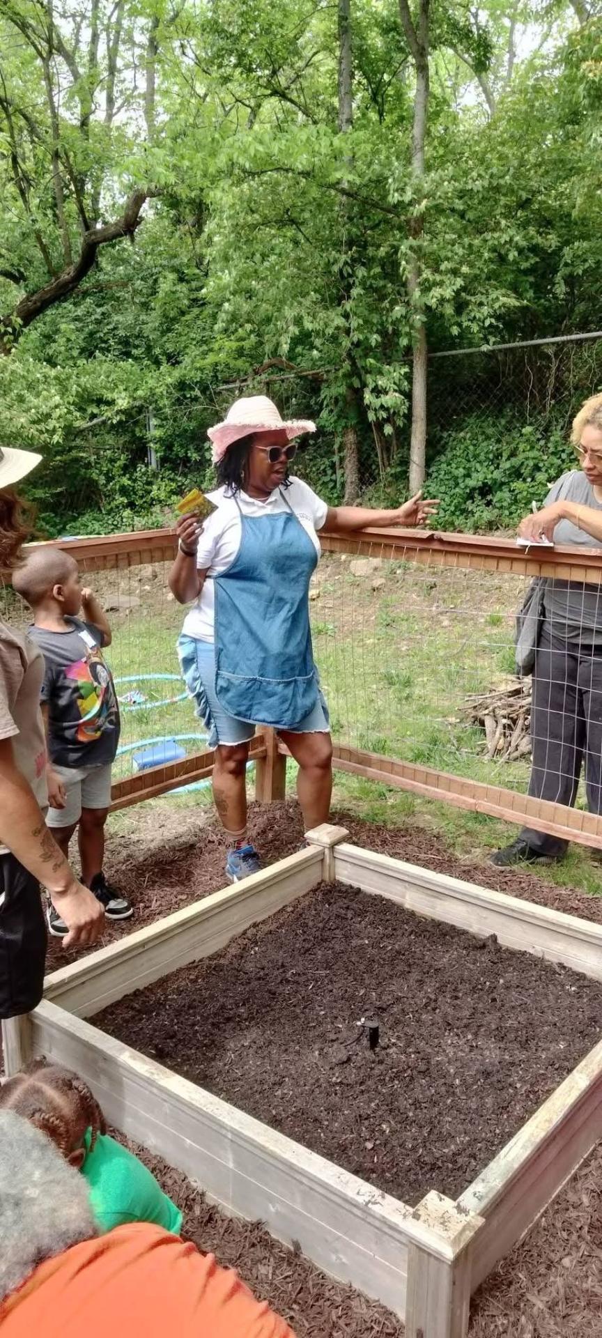 Shetika Davis leading a garden bed lesson with children and families